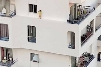 Toddler walks along floor ledge of apartment in spain